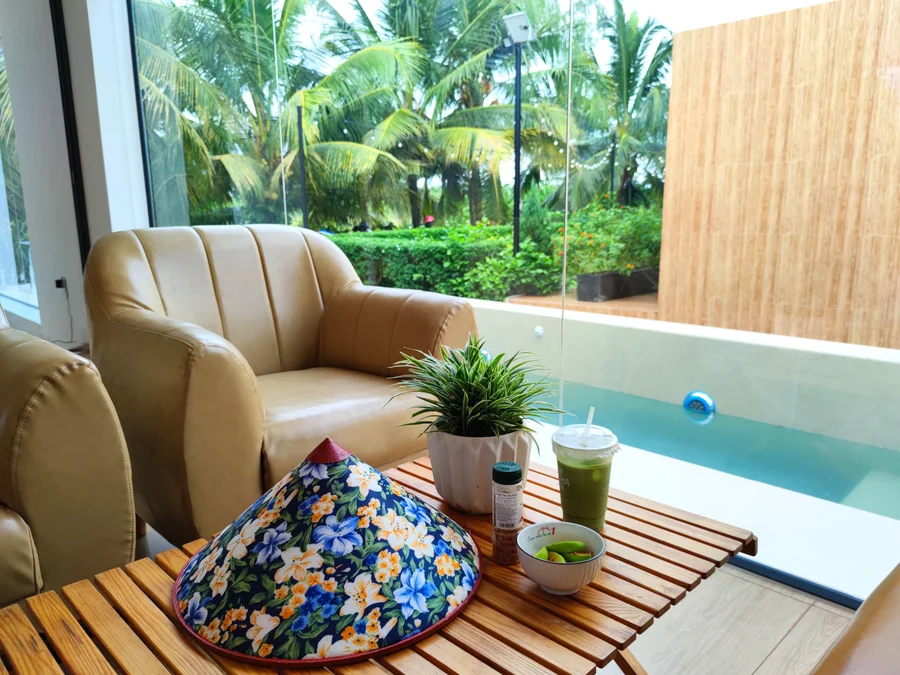 Góc thư giãn tại Go Cong Hideaway với bàn trà, ghế ngồi và view hồ bơi, lý tưởng để tận hưởng kỳ nghỉ cuối tuần.