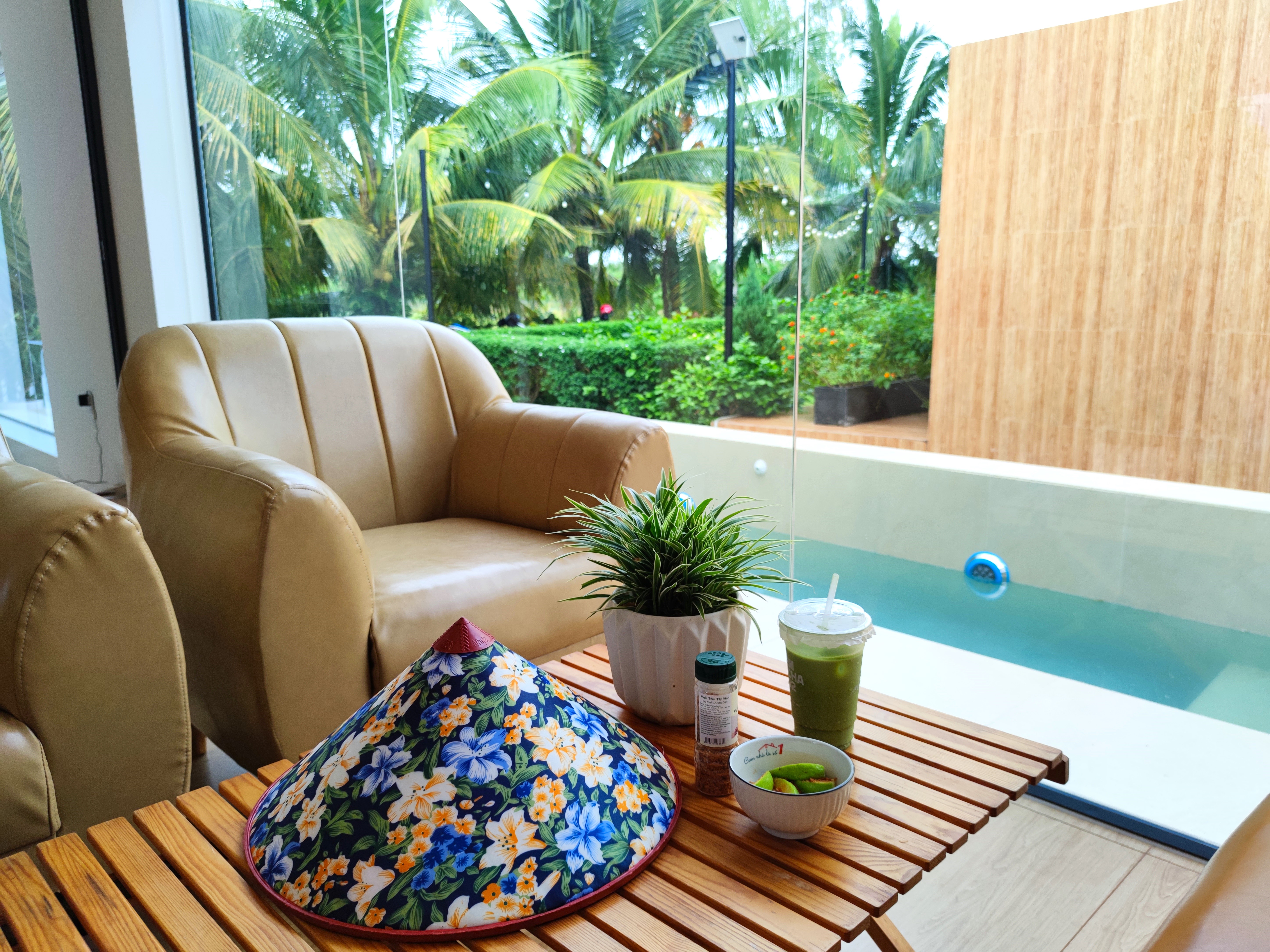 Góc thư giãn tại Go Cong Hideaway với bàn trà, ghế ngồi và view hồ bơi, lý tưởng để tận hưởng kỳ nghỉ cuối tuần.